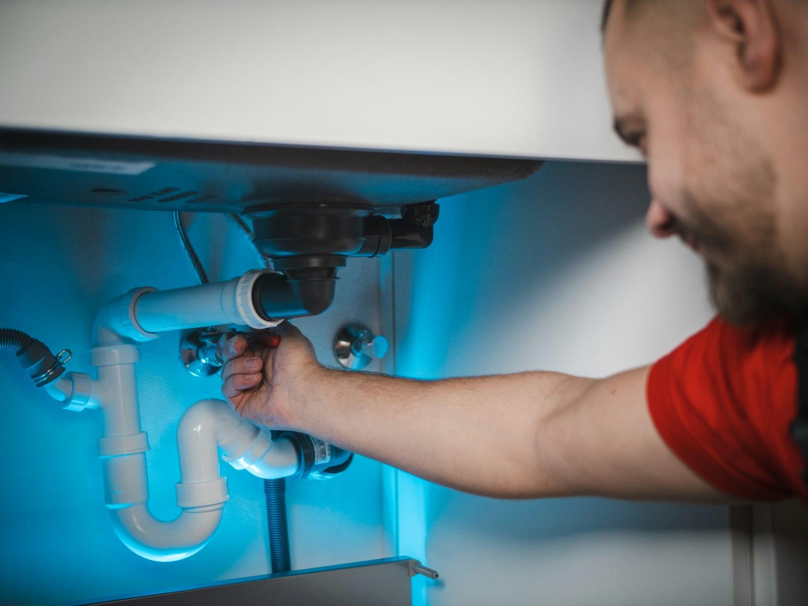 A technician repairing plumbing inside a home