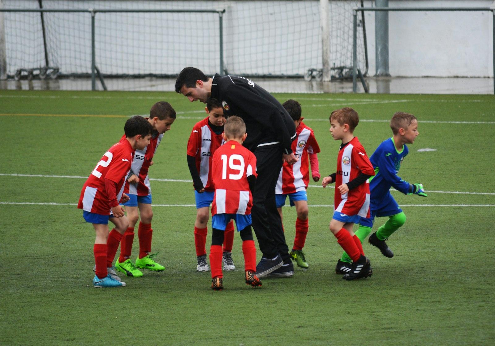 A coach huddles with a youth soccer team on the field